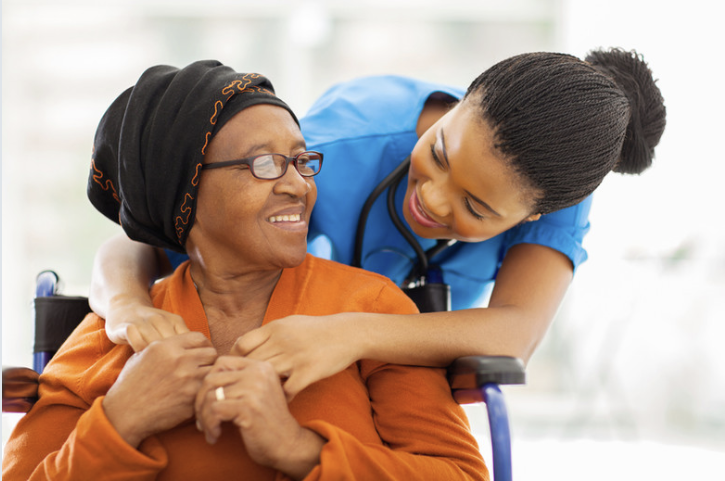 Compassionate caregiver hugging senior in wheelchair