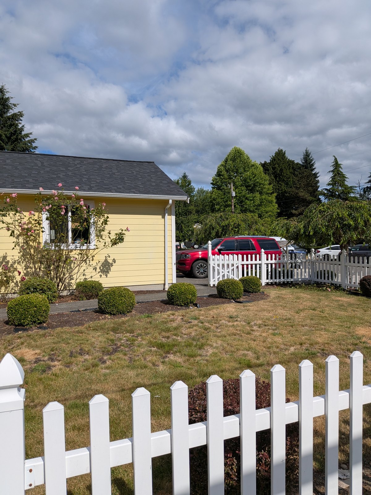 Lush front yard with white picket fence at Edmonds Villa adult family home in Edmonds